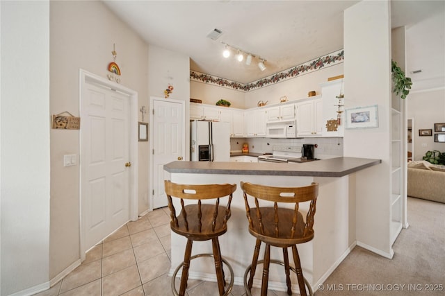 1101 S Yellowood Ave, Broken Arrow, OK 74012 - kitchen with white appliances, a peninsula, a breakfast bar, white cabinets, and dark countertops