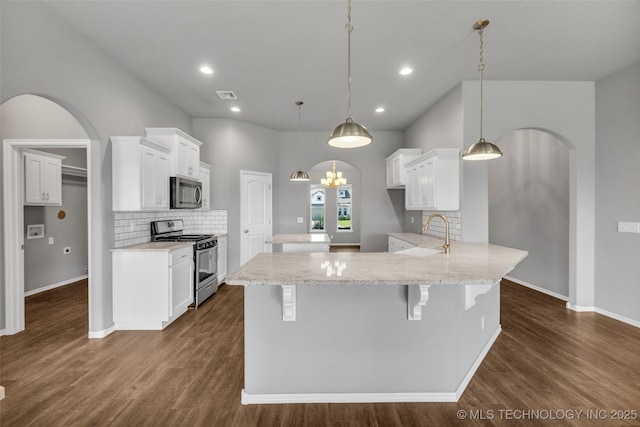 2012 W Huntsville Pl, Broken Arrow, OK 74011 - kitchen featuring appliances with stainless steel finishes, arched walkways, a peninsula, decorative backsplash, and dark wood finished floors