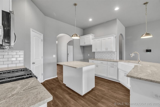 2012 W Huntsville Pl, Broken Arrow, OK 74011 - kitchen featuring arched walkways, backsplash, dark wood-type flooring, white cabinets, and recessed lighting