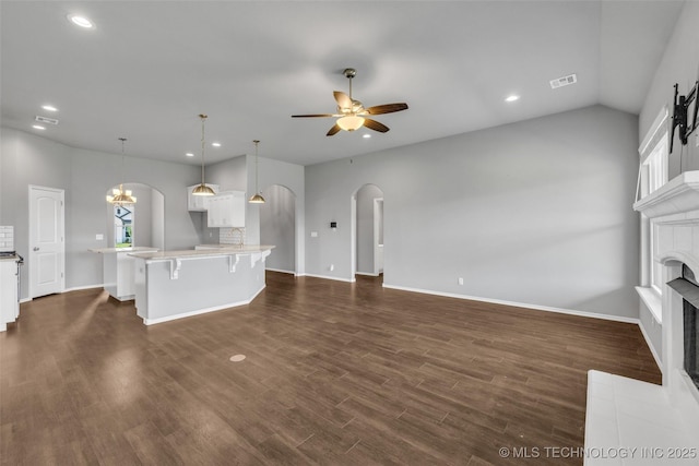 2012 W Huntsville Pl, Broken Arrow, OK 74011 - unfurnished living room with arched walkways, a ceiling fan, a tiled fireplace, recessed lighting, and dark wood-style floors