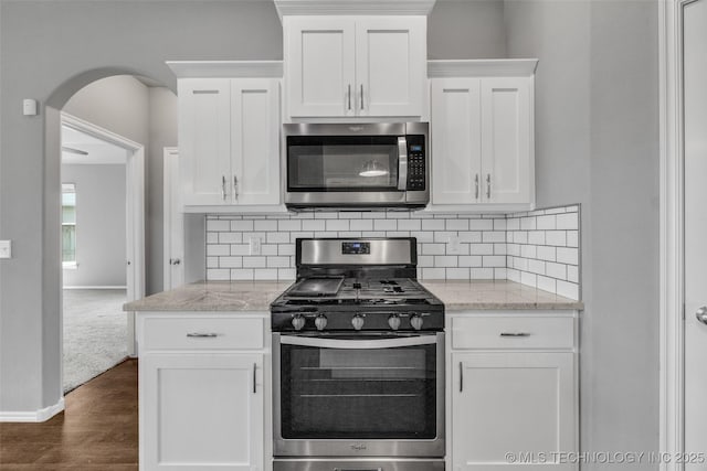 2012 W Huntsville Pl, Broken Arrow, OK 74011 - kitchen featuring appliances with stainless steel finishes, arched walkways, white cabinets, dark wood finished floors, and tasteful backsplash