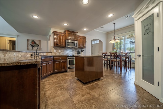 14701 E 150th St, Collinsville, OK 74021 - kitchen with stainless steel appliances, ornamental molding, backsplash, arched walkways, and dark stone counters