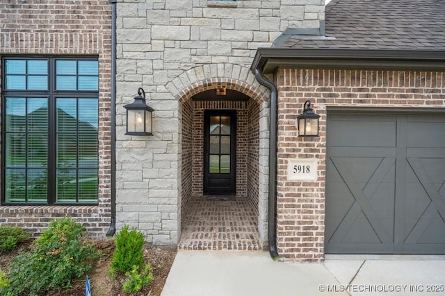 5918 E 126th Pl S, Bixby, OK 74008 - doorway to property featuring a garage, roof with shingles, and brick siding