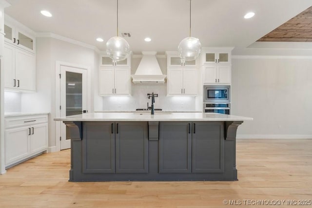 5918 E 126th Pl S, Bixby, OK 74008 - kitchen with custom range hood, appliances with stainless steel finishes, light countertops, ornamental molding, and an island with sink