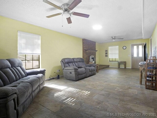 311 Washington Ave, Boswell, OK 74727 - living room featuring a ceiling fan, stone tile floors, a textured ceiling, and a fireplace