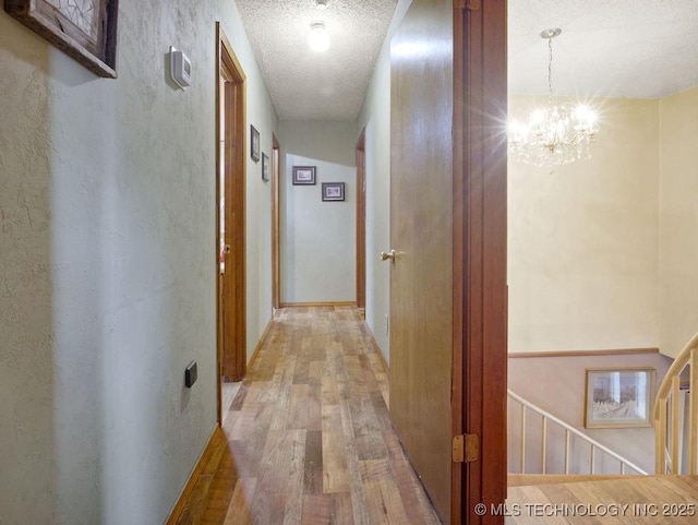 311 Washington Ave, Boswell, OK 74727 - hall with a chandelier, light wood finished floors, a textured ceiling, and an upstairs landing