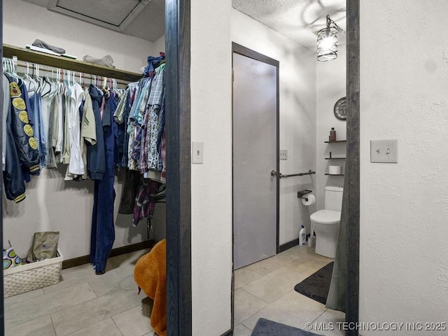 311 Washington Ave, Boswell, OK 74727 - bathroom with tile patterned floors, a walk in closet, a textured wall, and a textured ceiling