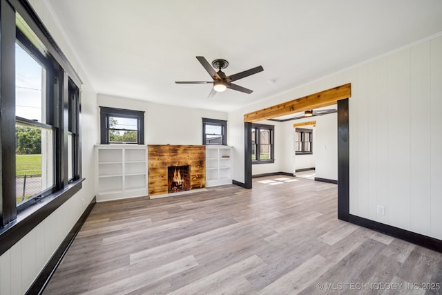 1119 W 7th St, Okmulgee, OK 74447 - unfurnished living room featuring a warm lit fireplace, light wood-type flooring, and ceiling fan