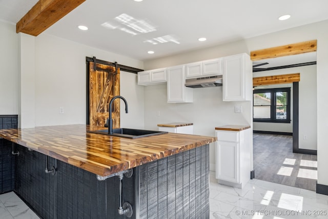 1119 W 7th St, Okmulgee, OK 74447 - kitchen featuring under cabinet range hood, butcher block countertops, white cabinets, recessed lighting, and a barn door