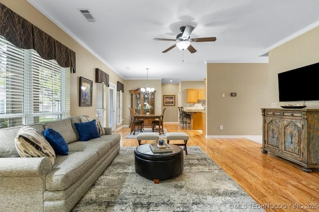 8306 E 77th Pl, Tulsa, OK 74133 - living room with light wood-type flooring, a ceiling fan, a chandelier, and crown molding