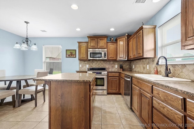 3705 W 107th Ct S, Jenks, OK 74037 - kitchen featuring appliances with stainless steel finishes, decorative backsplash, a kitchen island, light tile patterned flooring, and a chandelier