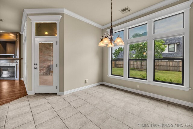 14651 S Gary Ave, Bixby, OK 74008 - unfurnished dining area featuring a chandelier, light tile patterned floors, crown molding, and a glass covered fireplace