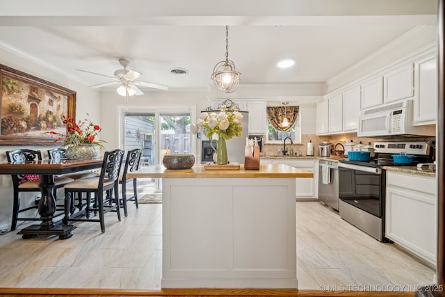 5612 S Newport Ave Unit 5612, Tulsa, OK 74105 - kitchen featuring appliances with stainless steel finishes, white cabinetry, ornamental molding, backsplash, and decorative light fixtures