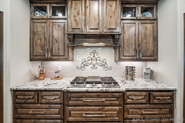3818 W Phoenix Pl, Broken Arrow, OK 74011 - kitchen with stainless steel gas stovetop, under cabinet range hood, backsplash, dark brown cabinets, and a textured wall