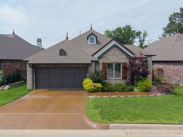 3818 W Phoenix Pl, Broken Arrow, OK 74011 - french country style house with stone siding, a garage, a front lawn, concrete driveway, and roof with shingles