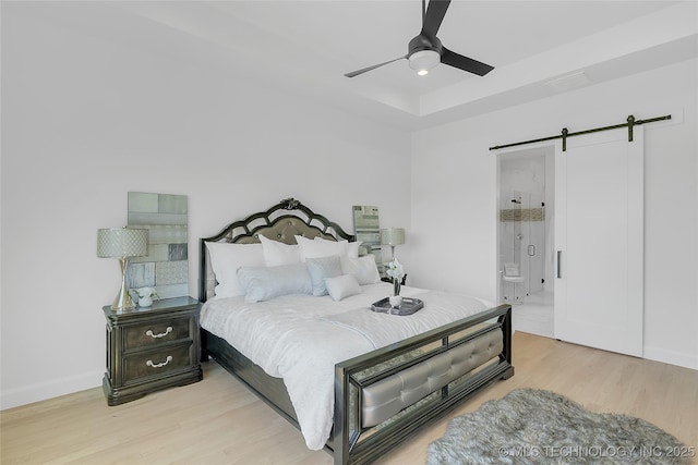12005 S Vandalia Ave, Tulsa, OK 74137 - bedroom featuring a barn door, light wood-style flooring, a tray ceiling, ceiling fan, and ensuite bathroom