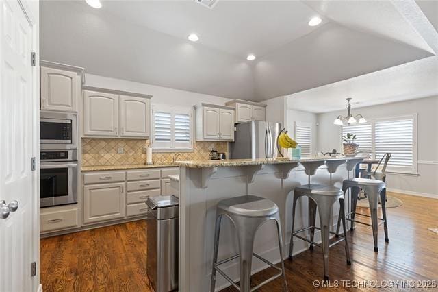 1516 W Trenton St, Broken Arrow, OK 74012 - kitchen featuring appliances with stainless steel finishes, a kitchen bar, healthy amount of natural light, backsplash, and lofted ceiling