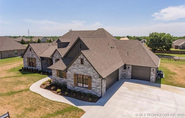 9022 N 65th Pl E, Owasso, OK 74055 - view of front of house featuring board and batten siding, concrete driveway, a front yard, and stone siding