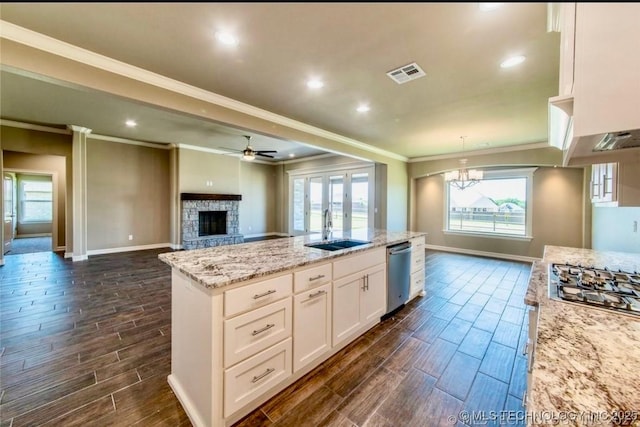 9022 N 65th Pl E, Owasso, OK 74055 - kitchen featuring appliances with stainless steel finishes, crown molding, wood tiled floors, a fireplace, and a ceiling fan