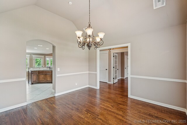 9200 E 92nd Pl, Owasso, OK 74055 - spare room with arched walkways, lofted ceiling, wood finished floors, and a chandelier