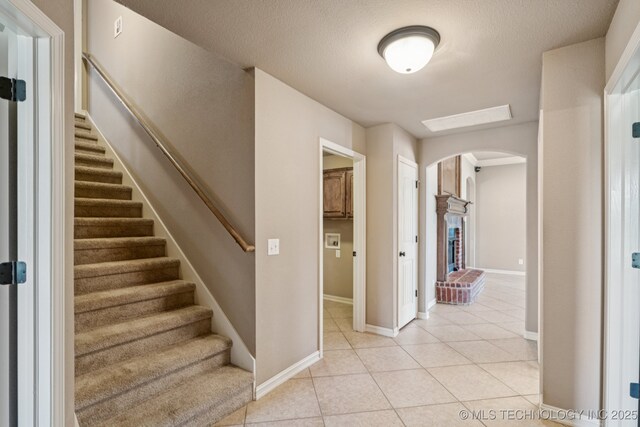 9200 E 92nd Pl, Owasso, OK 74055 - stairway with arched walkways, tile patterned floors, and a textured ceiling