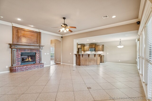 9200 E 92nd Pl, Owasso, OK 74055 - unfurnished living room with ceiling fan, crown molding, a brick fireplace, arched walkways, and recessed lighting