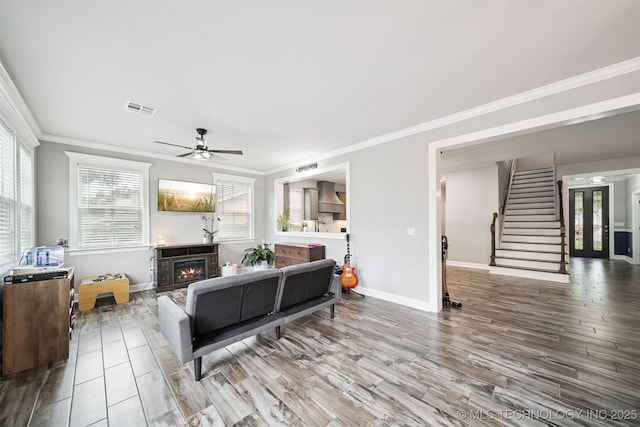 1909 W Nashville St, Broken Arrow, OK 74012 - living area featuring ornamental molding, a ceiling fan, stairway, wood finished floors, and a lit fireplace