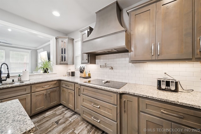 1909 W Nashville St, Broken Arrow, OK 74012 - kitchen with custom range hood, healthy amount of natural light, black electric stovetop, light wood finished floors, and ornamental molding