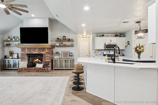 1112 N Yellowood Ave, Broken Arrow, OK 74012 - kitchen featuring stainless steel microwave, ceiling fan, lofted ceiling, light wood-style floors, and white cabinets