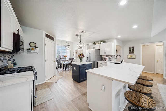 1112 N Yellowood Ave, Broken Arrow, OK 74012 - kitchen with stainless steel appliances, white cabinets, light wood finished floors, a kitchen breakfast bar, and a peninsula