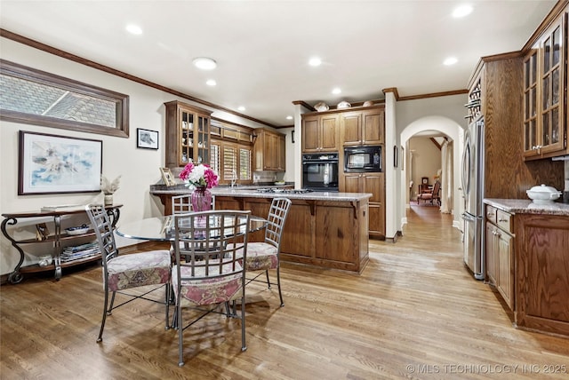 9632 S Vandalia Ave, Tulsa, OK 74137 - kitchen with black appliances, arched walkways, ornamental molding, a peninsula, and brown cabinets