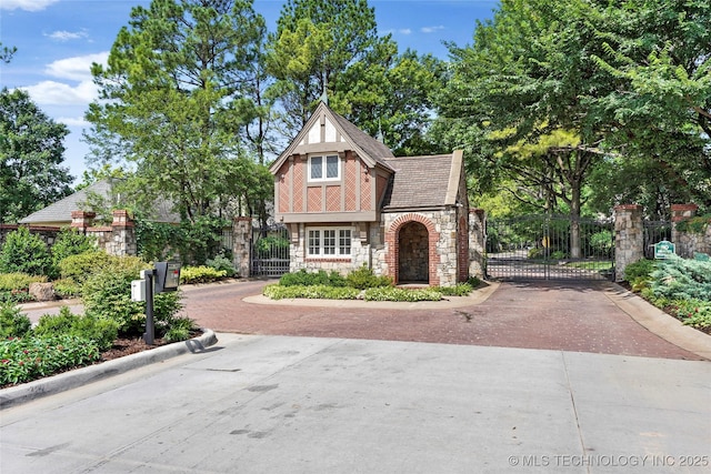 9632 S Vandalia Ave, Tulsa, OK 74137 - tudor home featuring stone siding, a gate, and driveway