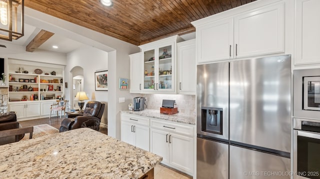 7920 N 147th E Ave, Owasso, OK 74055 - kitchen with appliances with stainless steel finishes, open floor plan, arched walkways, glass insert cabinets, and light stone counters
