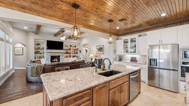 7920 N 147th E Ave, Owasso, OK 74055 - kitchen with appliances with stainless steel finishes, arched walkways, ceiling fan, a wooden ceiling with exposed beams, and glass insert cabinets