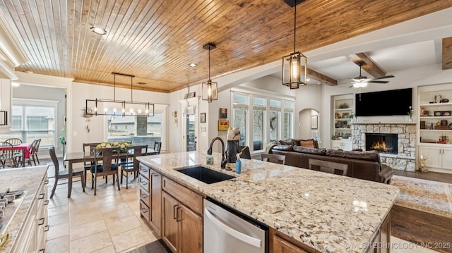 7920 N 147th E Ave, Owasso, OK 74055 - kitchen featuring stainless steel appliances, a stone fireplace, a ceiling fan, a kitchen island with sink, and light stone counters