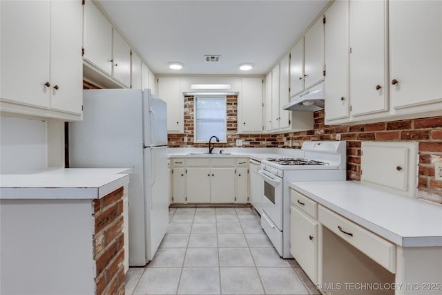 1417 Downing St, Oklahoma City, OK 73120 - kitchen with white appliances, under cabinet range hood, light tile patterned floors, light countertops, and white cabinets