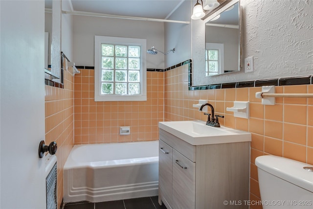 1417 Downing St, Oklahoma City, OK 73120 - bathroom with vanity, shower / bathtub combination, tile walls, tile patterned floors, and a wainscoted wall