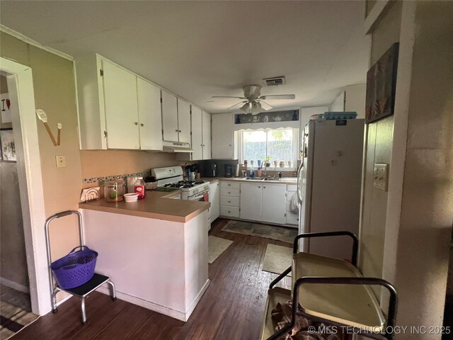106 N Jordan St, Cleveland, OK 74020 - kitchen featuring white appliances, under cabinet range hood, dark wood-style floors, ceiling fan, and white cabinets