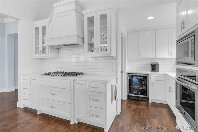 7107 E 88th St N, Owasso, OK 74055 - kitchen with appliances with stainless steel finishes, premium range hood, beverage cooler, white cabinets, and recessed lighting