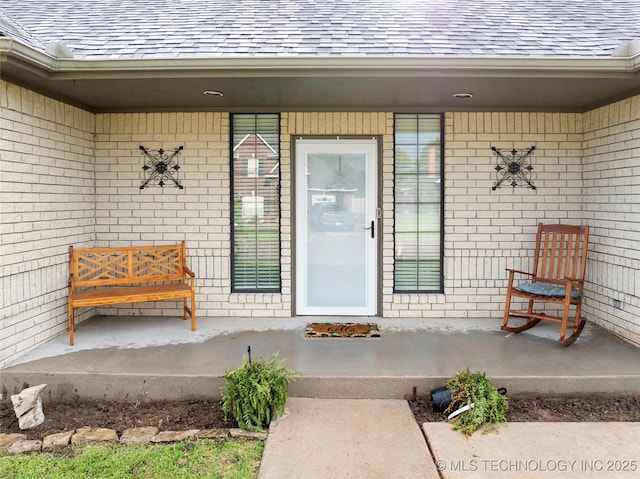 1507 Southern Hills Dr, Ardmore, OK 73401 - view of exterior entry with brick siding, a shingled roof, and a porch
