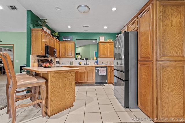 1507 Southern Hills Dr, Ardmore, OK 73401 - kitchen featuring appliances with stainless steel finishes, decorative backsplash, light countertops, a peninsula, and light tile patterned flooring