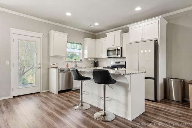 26806 E 143rd St S, Coweta, OK 74429 - kitchen with appliances with stainless steel finishes, white cabinetry, ornamental molding, dark wood-type flooring, and light stone countertops