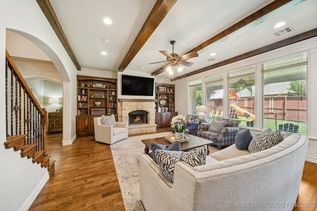 9545 E 108th St S, Bixby, OK 74133 - living room featuring a ceiling fan, a fireplace, wood finished floors, beamed ceiling, and stairway
