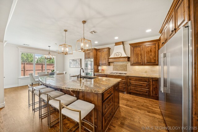 9545 E 108th St S, Bixby, OK 74133 - kitchen with stainless steel appliances, custom range hood, dark wood-type flooring, tasteful backsplash, and a kitchen breakfast bar