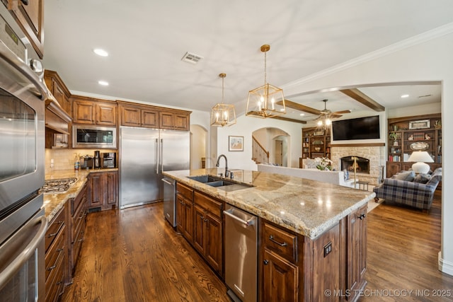 9545 E 108th St S, Bixby, OK 74133 - kitchen with built in appliances, a ceiling fan, arched walkways, a fireplace, and dark wood-style floors