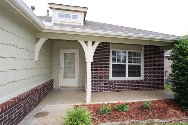 14313 E 112th Pl, Owasso, OK 74055 - view of exterior entry featuring a shingled roof and brick siding