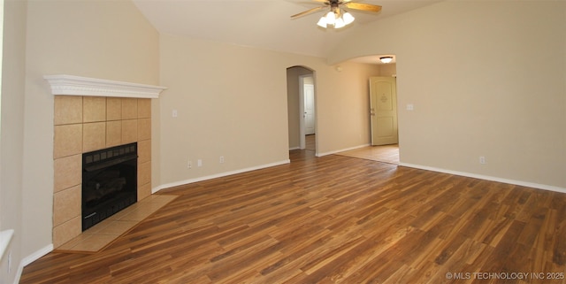 14313 E 112th Pl, Owasso, OK 74055 - unfurnished living room featuring arched walkways, ceiling fan, lofted ceiling, a tiled fireplace, and wood finished floors