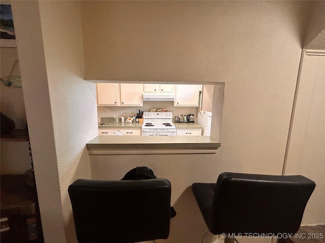 3402 S Winston Ave Unit 103, Tulsa, OK 74135 - kitchen with electric stove, under cabinet range hood, white cabinets, and a textured wall
