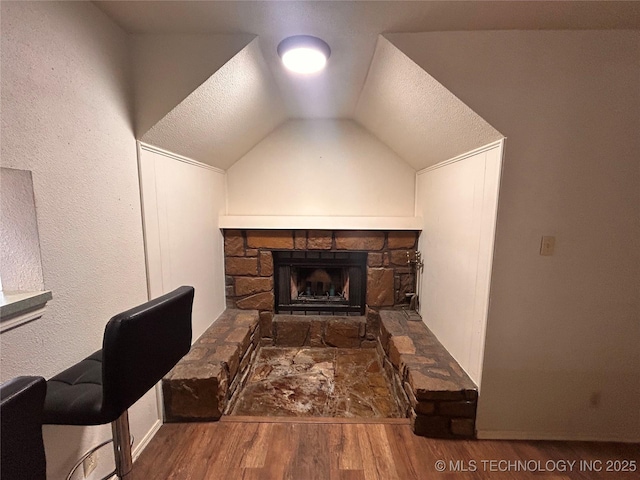3402 S Winston Ave Unit 103, Tulsa, OK 74135 - interior space with wood finished floors, a stone fireplace, vaulted ceiling, and a textured ceiling