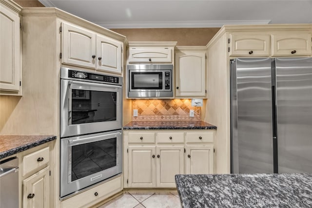 4405 Ithica St, Broken Arrow, OK 74012 - kitchen with stainless steel appliances, cream cabinetry, dark stone counters, backsplash, and light tile patterned flooring